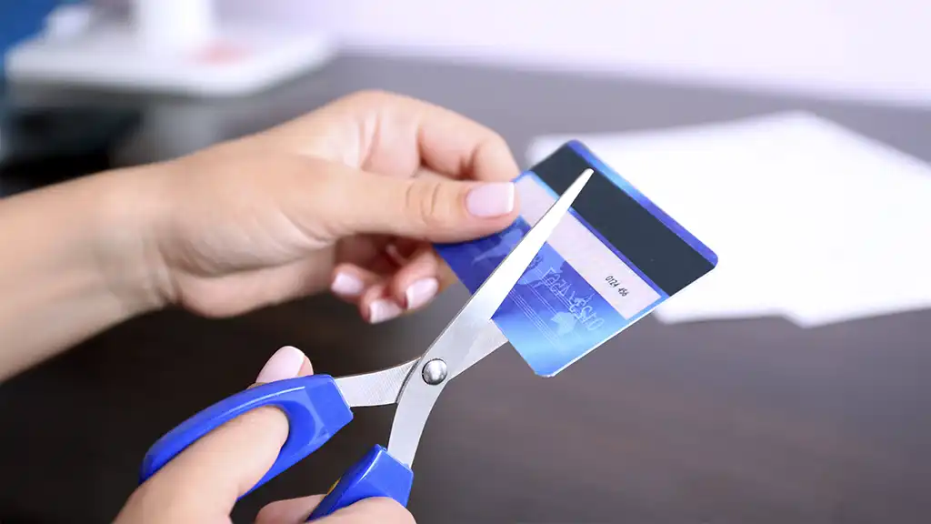 Tesoura cortando um cartão de crédito para simbolizar o fim da dívida no cartão após os gastos de Natal.